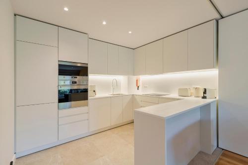 a white kitchen with white cabinets and appliances at Quinta View Apartment in Setúbal