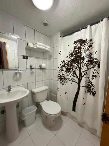 a bathroom with a toilet and a tree shower curtain at Hotel Plaza Colon in Arica
