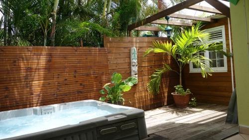 a hot tub in a backyard with a wooden fence at Les Flibustiers in Sainte-Anne