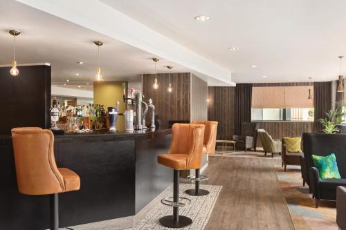 a bar in a hotel with orange bar stools at Ramada Hotel & Suites by Wyndham Coventry in Coventry