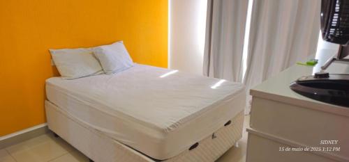 a bed with white sheets and pillows in a room at Apartamento Centro à 100 metros da Praça da Matriz in Boituva