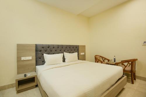 a bedroom with a large white bed and a table at Hotel Melano Ambala Chandigarh Rd Zirakpur SkyJumper park in Zirakpur