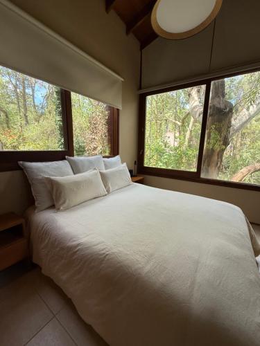 a bedroom with a large white bed with two windows at Casa Azul in Mar de las Pampas