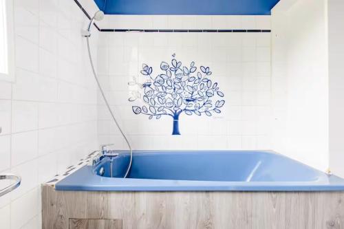 a blue tub in a bathroom with a tree sticker on the wall at Chez Joséphine et Pierre in Cassel
