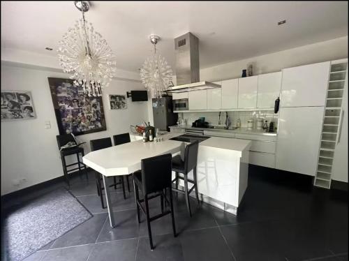 kuchnia z białymi szafkami, stołem i krzesłami w obiekcie Chambre avec salle de bain et terrasse dans un maison chaleureuse w mieście Nanterre