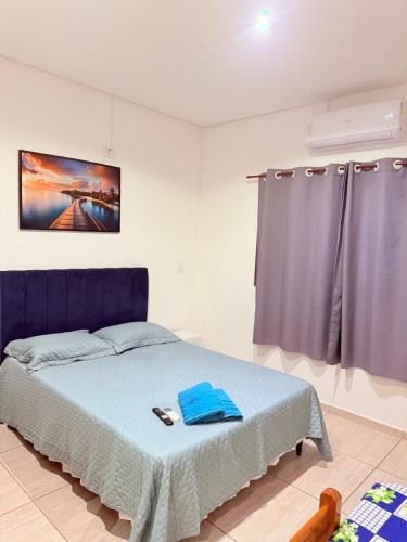 a bedroom with a blue bed and a window at Pousada ENCANTOS DO MAR in Ubatuba