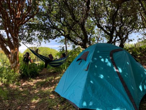 Un grupo de personas sentadas en una hamaca en una tienda de campaña. en Muelle del Tiempo Camping, en Quilán