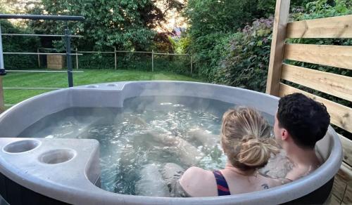 Un uomo e una donna seduti in una vasca idromassaggio di Le studio de la Noire Choque - Bain nordique ad Audembert