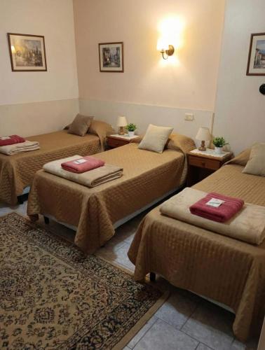 Ein Zimmer mit drei Betten, braunen Decken und einem Teppich. in der Unterkunft KIN Hotel in Villa Carlos Paz