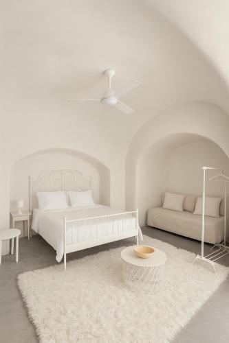 a white bedroom with a bed and a table at Unique small stonehouse at Thira in Megalochori