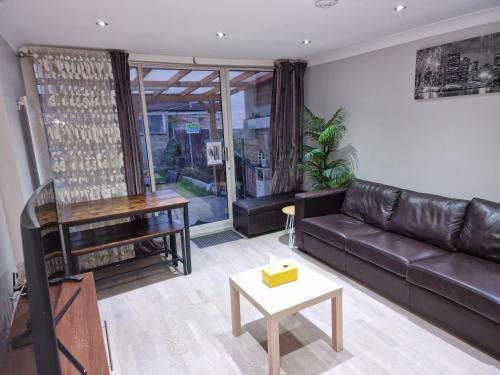a living room with a leather couch and a piano at NightRest Homes Smart TV In Each Room - Parking - Hemel Hempstead in Hemel Hempstead