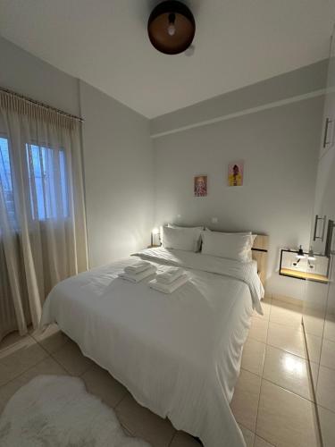 una camera da letto bianca con un grande letto bianco e una finestra di Central stay a Larisa