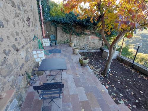 a patio with chairs and a table and a tree at La Dimora di Dida in Seggiano