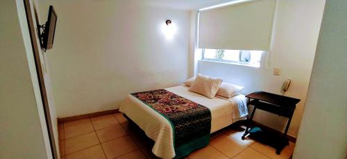 a small bedroom with a bed and a window at Hotel Villa Karina in Bogotá