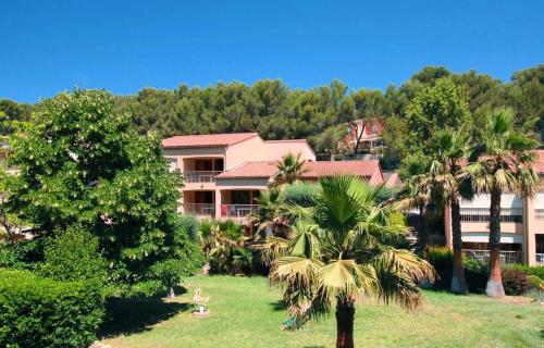 ein Resort mit Palmen vor einem Gebäude in der Unterkunft Le Nid du Vallon -studio- Plage & Piscine in Sanary-sur-Mer