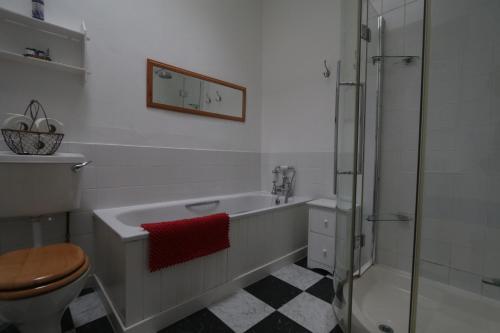 een badkamer met bad, douche en toilet bij Moir Cottage in Portpatrick