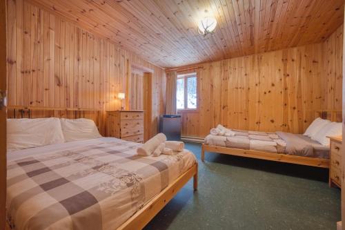 a bedroom with two beds in a wooden cabin at Chalet Saumon with Private SPA for 16 Guests , Skiing in Saint-Paul-de-Montminy