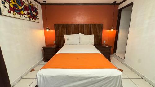 a small bedroom with a bed with an orange wall at HOTEL ZAPOTLAN in Ciudad Guzmán