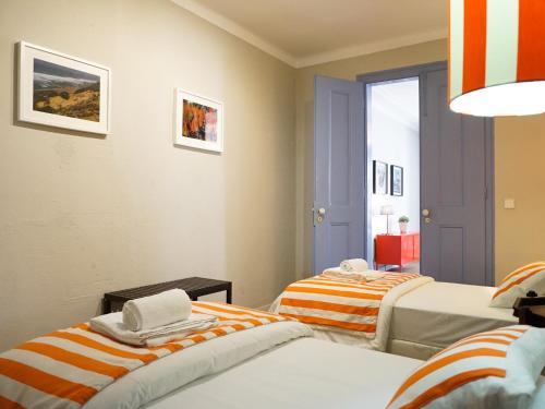 2 camas en una habitación con rayas anaranjadas y blancas en Combro by Patio 25, en Lisboa