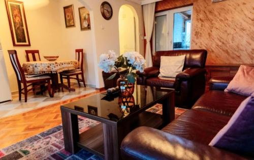 sala de estar con muebles de cuero y mesa en Milenijum apartman, en Podgorica