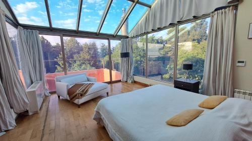 a bedroom with a bed and a chair and a large window at Hotel Boutique Casa de Campo Potrero de los Funes a 30min in Estancia Grande