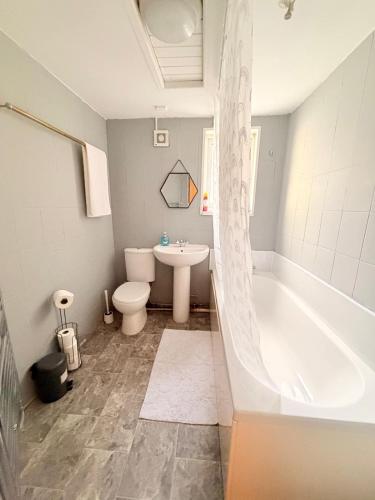 ein Badezimmer mit Badewanne, Toilette und Waschbecken in der Unterkunft A cozy, comfortable, calm house perfect for groups in Swansea