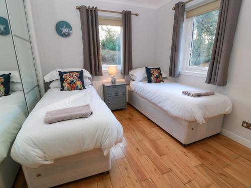 two beds in a room with two windows at Cramar Cottage in Glasgow