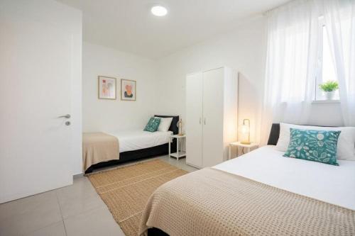 阿什杜德Luxury 5 Rooms Apartments 3 minutes from beach的一间带两张床和一扇窗户的白色卧室