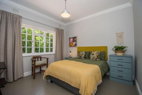 a bedroom with a bed and a dresser and a window at Sunny Poolside Escape in Somerset West in Somerset West