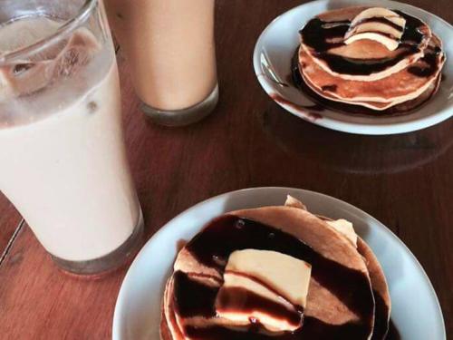 a table with two plates of pancakes and a glass of milk at Jurisu Resort in San Vicente