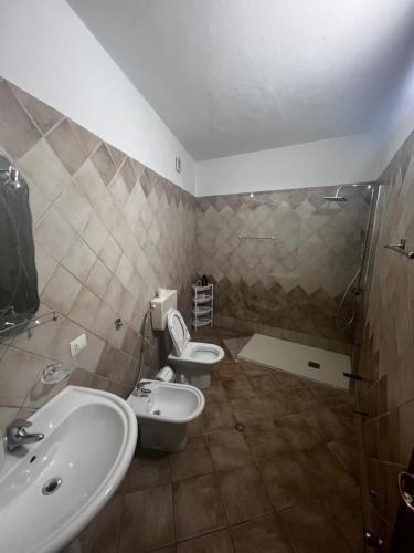 un bagno con due wc, un lavandino e una doccia di Hana's Apartment a Durrës