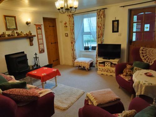 Una sala de estar con muebles rojos y un televisor. en Carnowen Cottage, en Ringsend