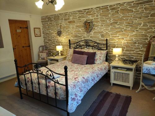 a bedroom with a bed and a stone wall at Carnowen Cottage in Ringsend