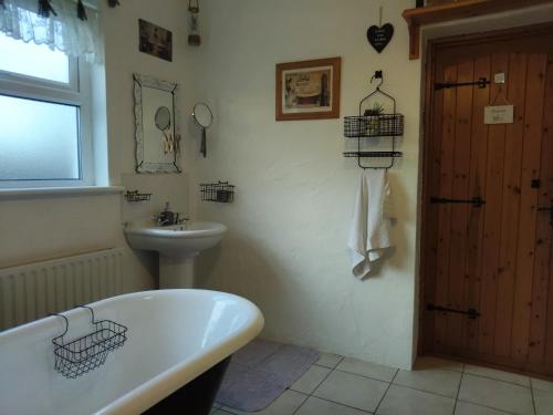 un baño con bañera y lavabo en Carnowen Cottage, en Ringsend