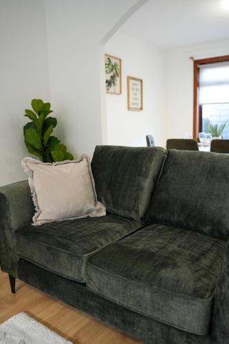 a green couch in a living room with a pillow at Nigel House in Livingston