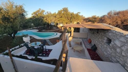 een patio met een zwembad en een parasol bij Ez-zine Glam in El Aadamna