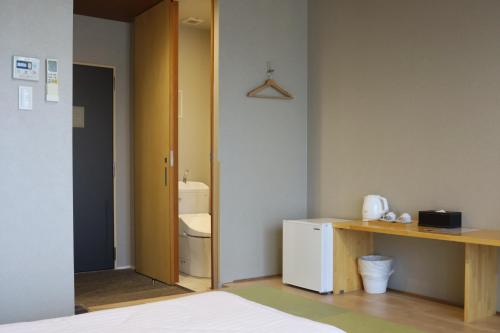 a room with a bathroom with a toilet and a desk at Kansai Airport Hotel Pine Villa in Kansai International Airport