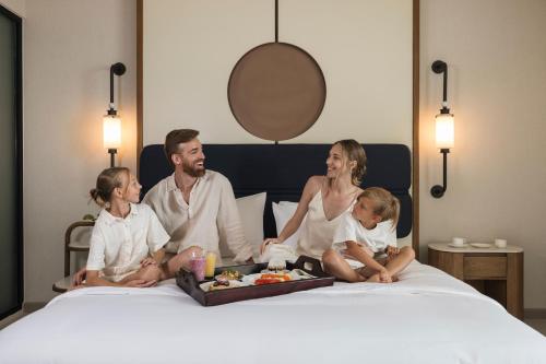 uma família sentada em uma cama com uma bandeja de comida em AVA Resort Cancun - All Inclusive em Cancún