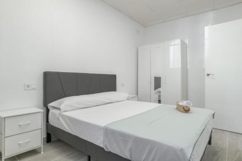 a white bedroom with a large bed and a nightstand at Apartamento Ajm in Barbate