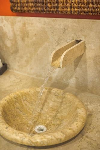 a stone sink with water pouring out of a wooden practition at HOTEL CARASOL VILLAS & SUITES in Ciudad Madero