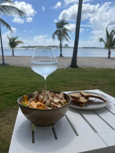 een kom met eten en een glas wijn op tafel bij Les pieds dans l'eau in Baie Nettle