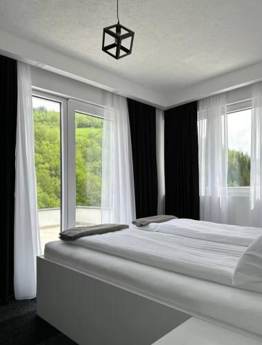 a bedroom with a large white bed with windows at Vila Amore Sarajevo Bjelasnica 