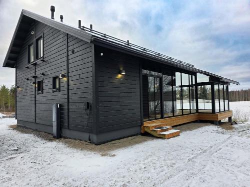 Ein schwarzes Haus im Schnee mit vielen Fenstern in der Unterkunft Villa Taipale - 8hlö, Himosranta in Jämsä
