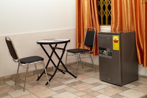 two chairs and a table next to a table and a refrigerator at Royal prima guest house, apartment and event center in Amanfro