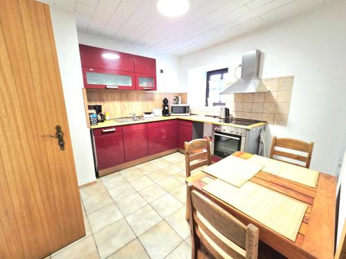 帕彭海姆Ferienwohnung an der Altmühl - Apartment Hollerstein的厨房配有红色橱柜和带桌子的木桌