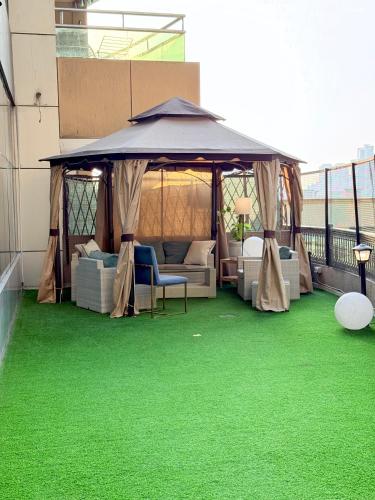 a gazebo on a balcony with green grass at Best Place Holiday Home IIII Free Parking in Ajman