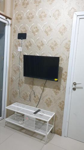 a flat screen tv hanging on a wall at Properti9 at Apartemen Green Pramuka in Jakarta