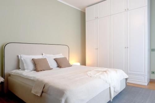 a white bedroom with a white bed with pillows at Urban Deluxe Calea Victoriei 100 Sauna and Jacuzzi in Bucharest