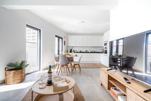 Una cocina con gabinetes blancos y una mesa y sillas. en Casa Inglesa 1, en Portimão