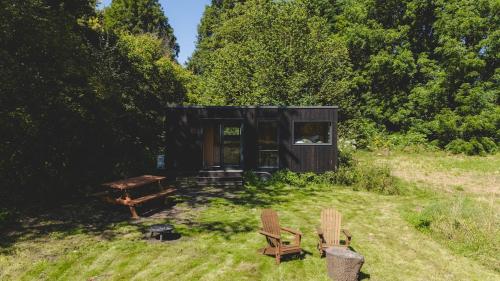 Eine Hütte auf einem Feld mit Picknicktisch und Stühlen in der Unterkunft Parcel Tiny House I Richecourt vue Lac in Mesbrecourt-Richecourt